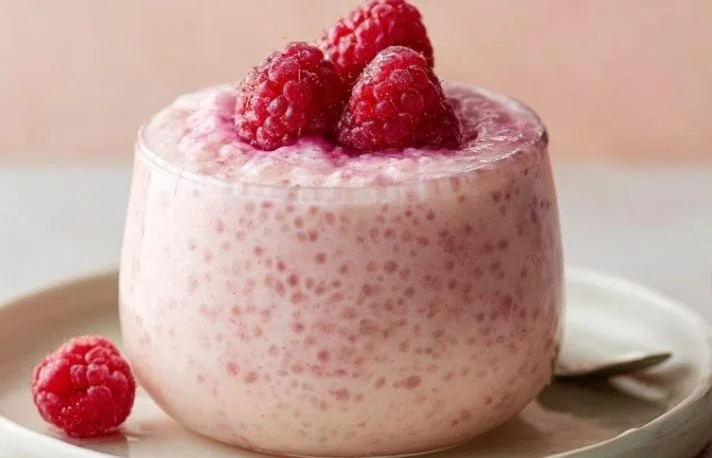 Delicious vanilla raspberry chia pudding in a glass topped with fresh raspberries
