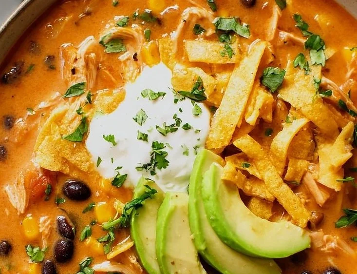 Bowl of classic chicken tortilla soup with avocado and tortilla strips