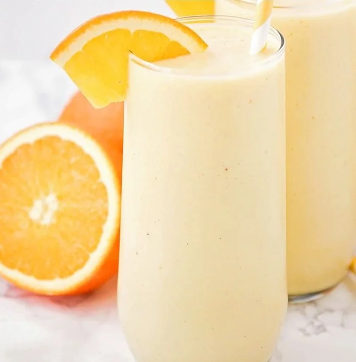 Delicious orange creamsicle smoothie in a glass with a straw.