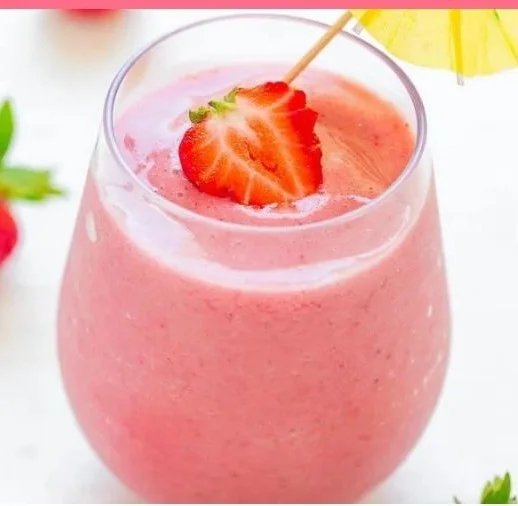 Strawberry pineapple smoothie in a glass with fresh fruit around