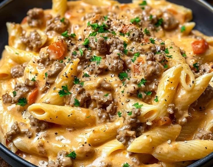 Creamy beef pasta dish served in a bowl with garnishes